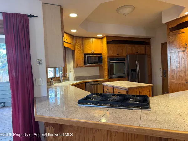 a kitchen with stainless steel appliances granite countertop a refrigerator a stove and a sink with wooden cabinets