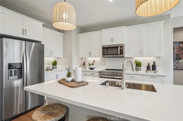 a kitchen with stainless steel appliances a stove a refrigerator a sink a stove a microwave and cabinets