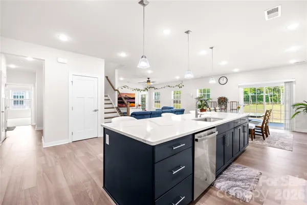 a large kitchen with kitchen island a sink dishwasher a stove a dining table and chairs with wooden floor