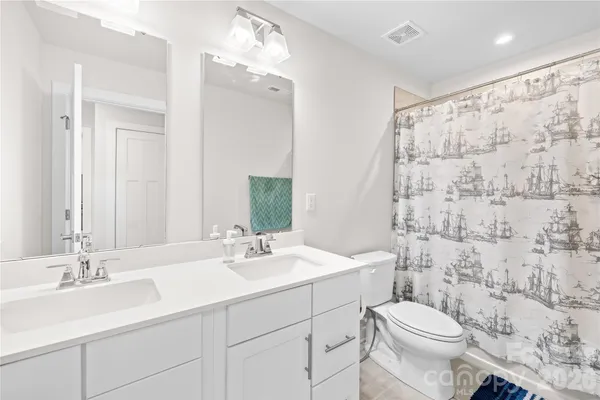 a bathroom with a sink toilet double vanity and shower