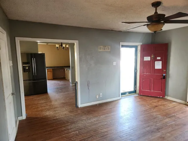 an empty room with wooden floor closet and windows