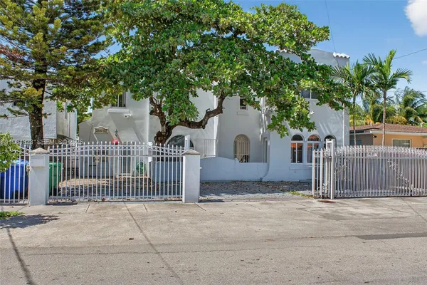 a white house that has a tree in front of it