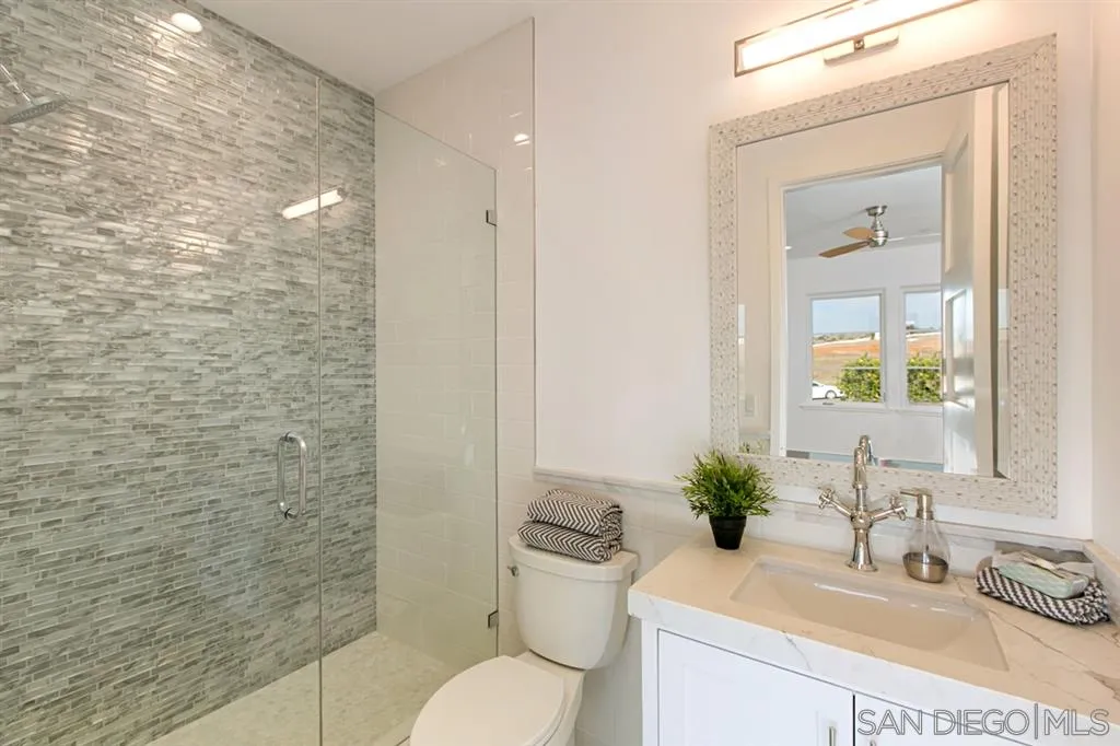 16582 Rio Vista Road San Diego, CA 92127 - Photo 13 of 20 a bathroom with a granite countertop sink a toilet and shower