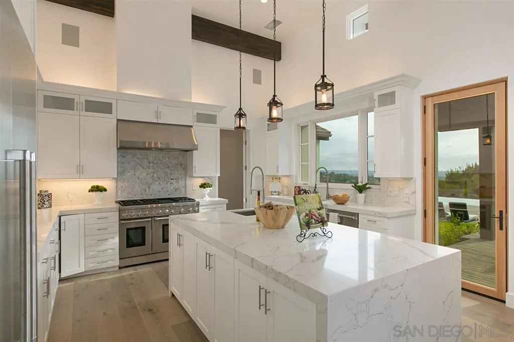 16582 Rio Vista Road San Diego, CA 92127 - Photo 6 of 20 a large kitchen with kitchen island a large counter top space a sink stainless steel appliances and cabinets