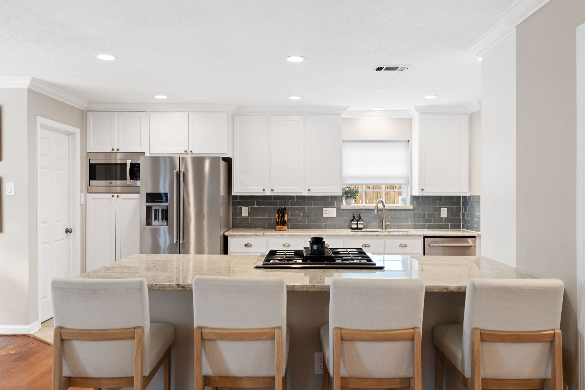 991 Curtin Street Houston, TX 77018 - Photo 9 of 39 The kitchen is light and bright with its classic white cabinetry and light stone countertops. A double paned window overlooking the driveway makes it easy to see little ones riding bikes while at the kitchen sink. Laundry room located to the left through the closed door.