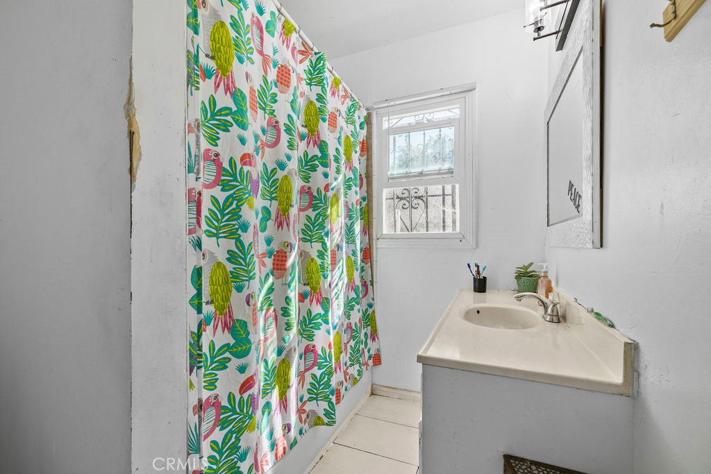4237 Abbott Road Lynwood, CA 90262 - Photo 13 of 39 a bathroom with a sink a mirror and a shower curtain