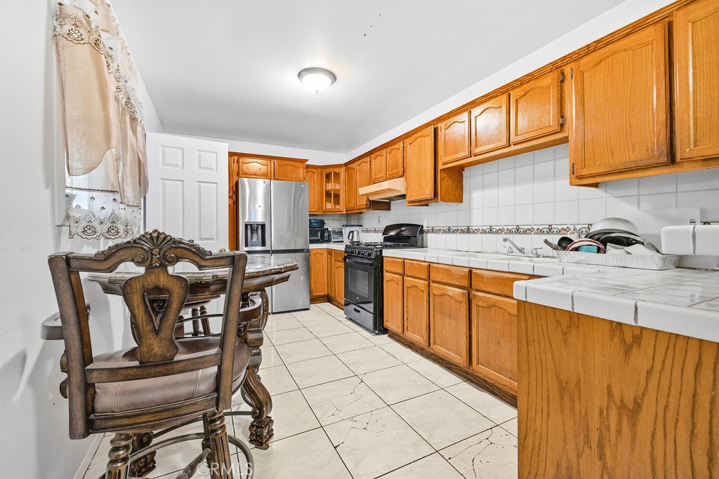 4237 Abbott Road Lynwood, CA 90262 - Photo 8 of 39 a kitchen with stainless steel appliances kitchen island granite countertop a table chairs in it and wooden floors