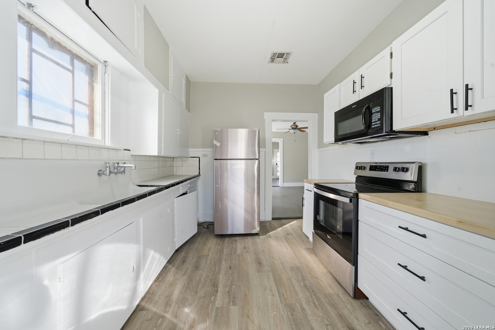 122 Biering Street, Unit 2 San Antonio, TX 78210 - Photo 6 of 8 a kitchen with a refrigerator a stove top oven a sink dishwasher and wooden floor