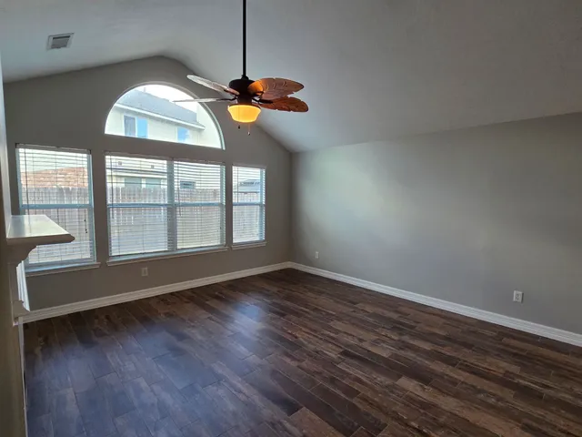 a view of an empty room with wooden floor and a window