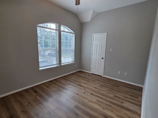 an empty room with wooden floor and windows