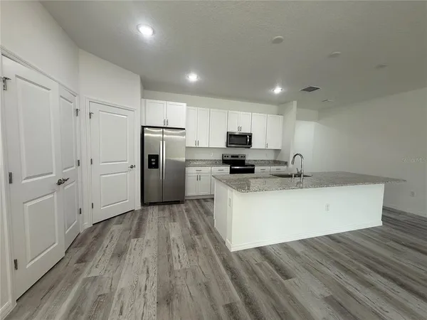 a kitchen with wooden floors white cabinets and stainless steel appliances