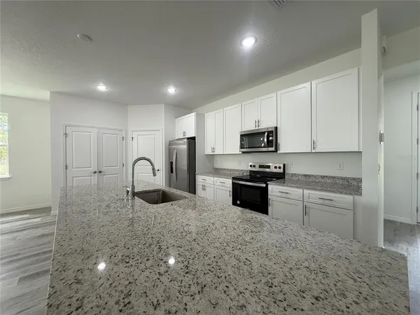 a kitchen with granite countertop white cabinets and stainless steel appliances