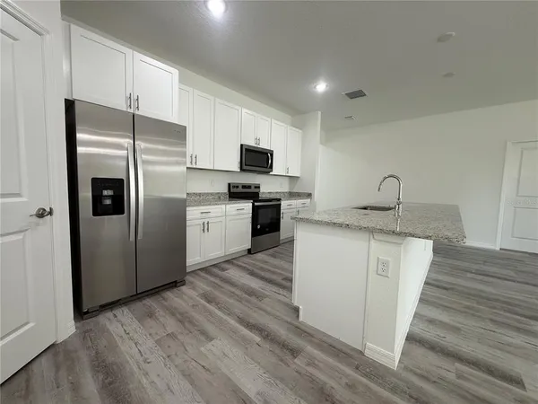 a kitchen with granite countertop a refrigerator stove and oven
