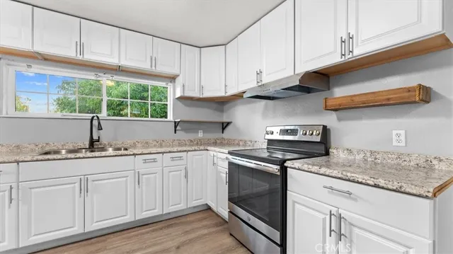 a kitchen with granite countertop white cabinets and a sink