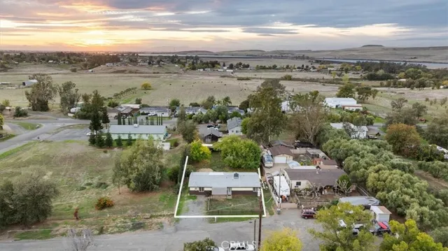 a backyard of a house with large trees and wooden fence
