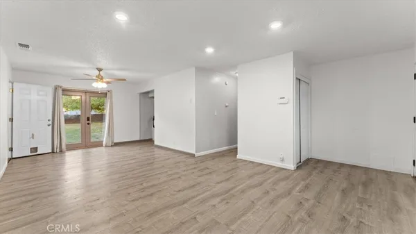 an empty room with wooden floor and entrance to ceiling window