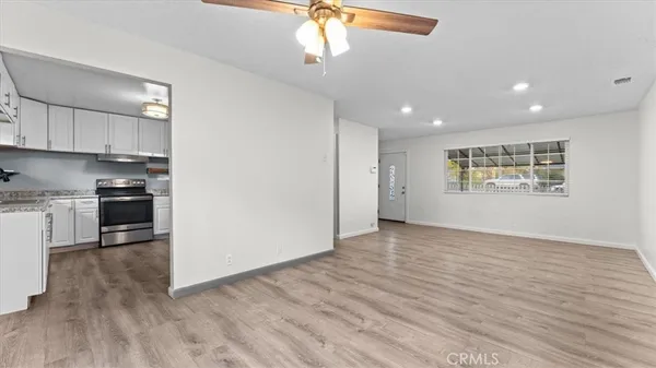 a view of empty room with wooden floor and kitchen