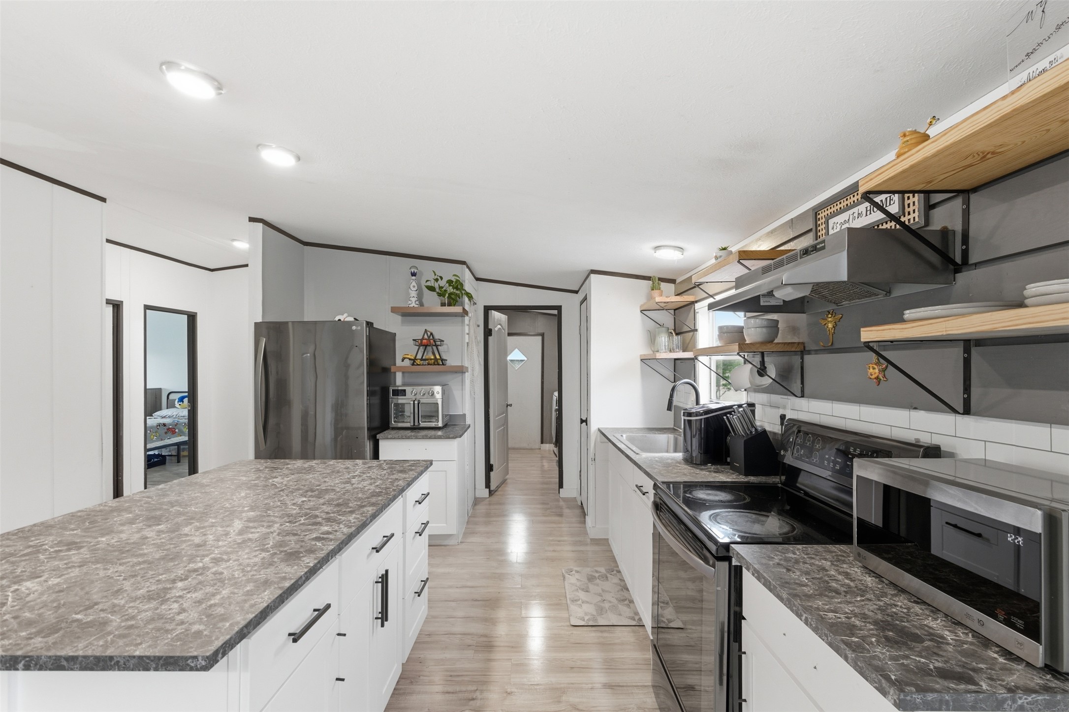 580 Railyard Drive Kyle, TX 78640 - Photo 8 of 20 The kitchen features a large island with a patterned countertop, white cabinetry with dark hardware, and light wood flooring