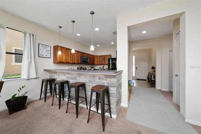 a view of kitchen with kitchen island granite countertop refrigerator and stove