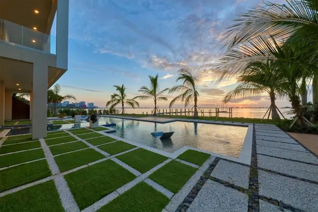 a view of swimming pool with a lounge chair and palm trees
