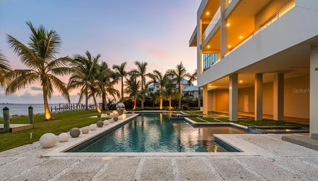 a view of swimming pool with a lounge chair and palm trees