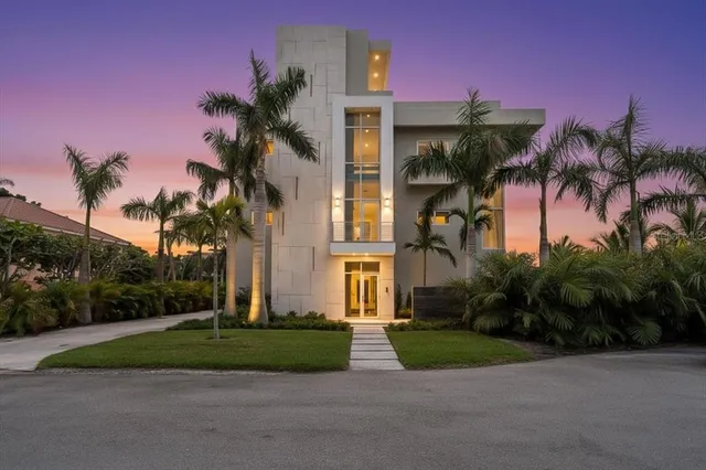 front view of a house with a yard and palm trees
