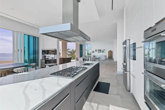 an open kitchen with granite countertop a stove dining table chairs and a refrigerator
