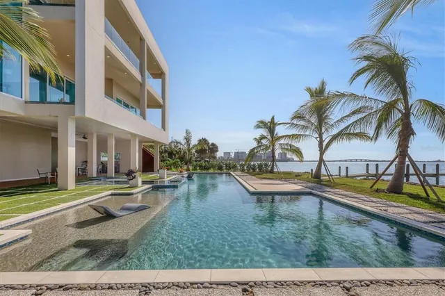 a view of small pool with lawn chairs and plants