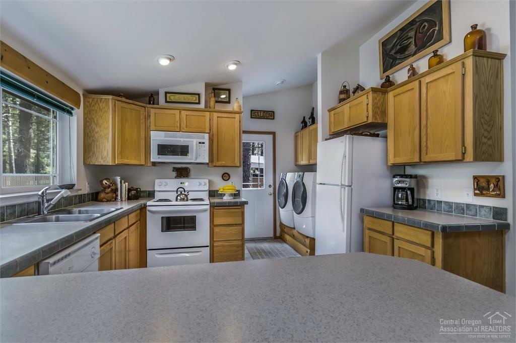 17171 Island Loop Way Bend, OR 97707 - Photo 16 of 25 a kitchen with stainless steel appliances granite countertop a refrigerator a stove top oven a sink dishwasher and white cabinets with wooden floor
