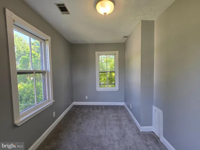 an empty room with windows and chandelier fan
