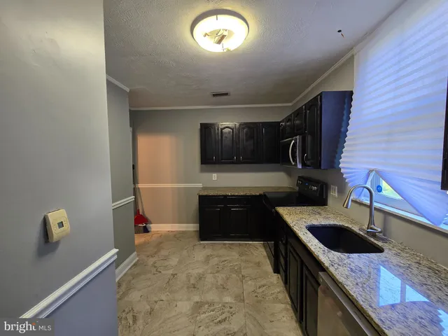 a view of a refrigerator in kitchen and an empty room