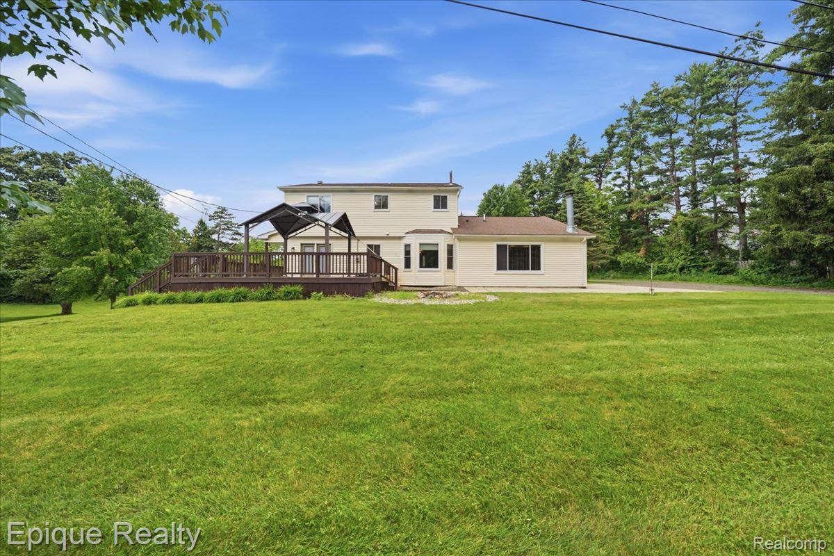 1221 Rhodes Road Lake Orion, MI 48360 - Photo 54 of 72 Expansive lawn area featuring a multi-level wood deck, a covered pergola, and mature perimeter trees