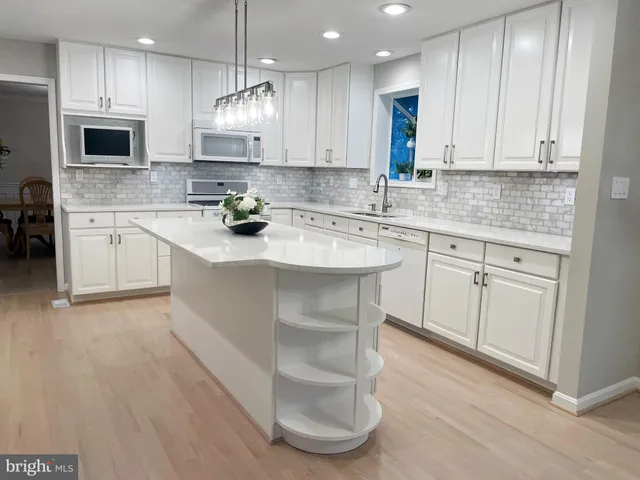 a kitchen with stainless steel appliances granite countertop a sink a stove a microwave and white cabinets