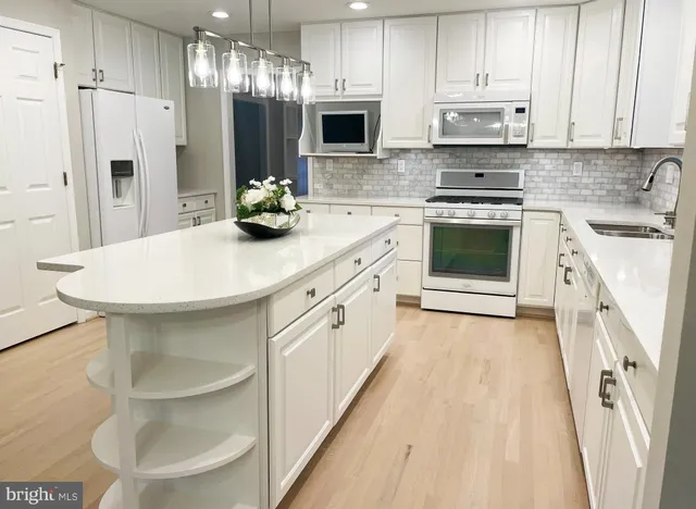 a kitchen with stainless steel appliances a white sink cabinets and wooden floor