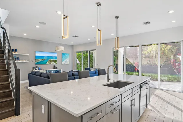 a kitchen with kitchen island a large counter top space appliances and a view of living room