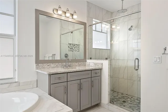 a bathroom with a granite countertop sink a shower and a mirror