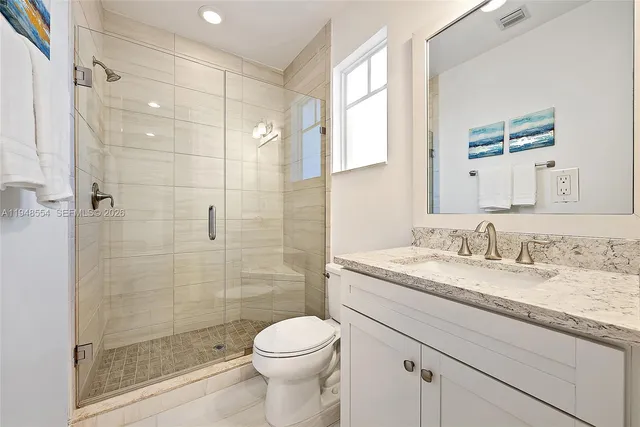 a bathroom with a granite countertop sink a toilet and shower