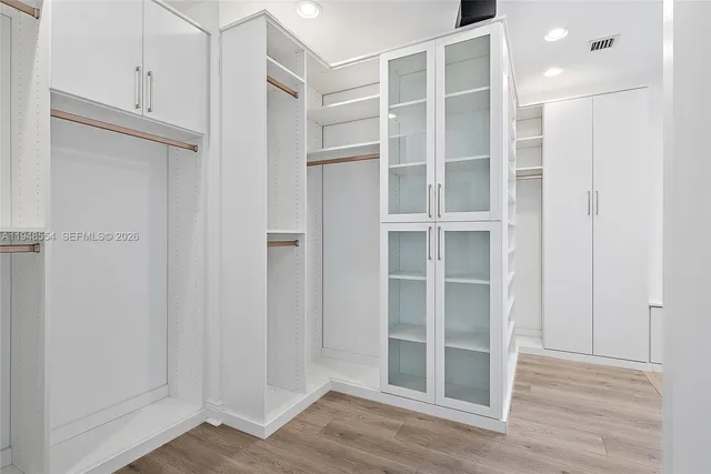 a view of an empty room with wooden floor and closet