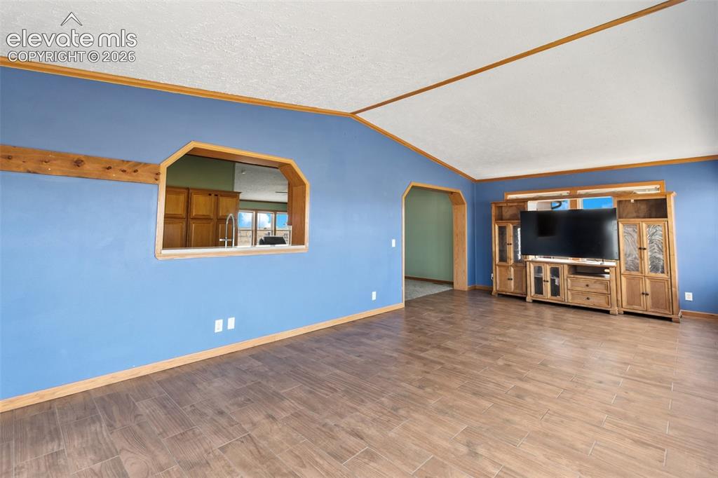 1350 South Calhan Highway Yoder, CO 80864 - Photo 13 of 45 Spacious living area featuring wood-finish flooring, vaulted ceilings, and a pass-through window with wood trim
