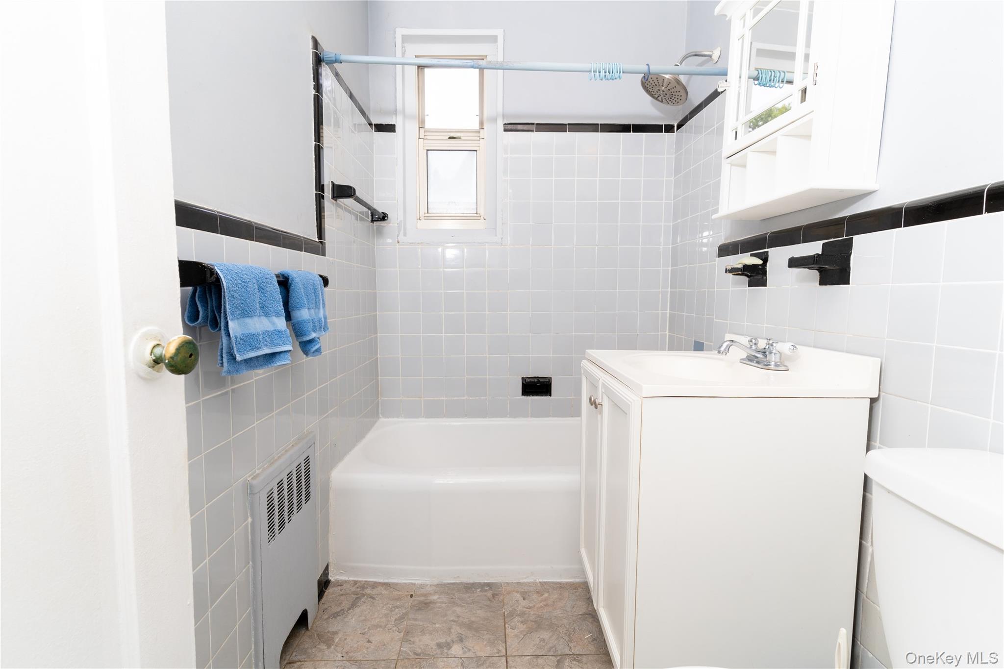 61-15 251st Street, Unit 1100 Queens, NY 11362 - Photo 12 of 17 Full bathroom featuring tile walls, bathtub / shower combination, radiator, and vanity