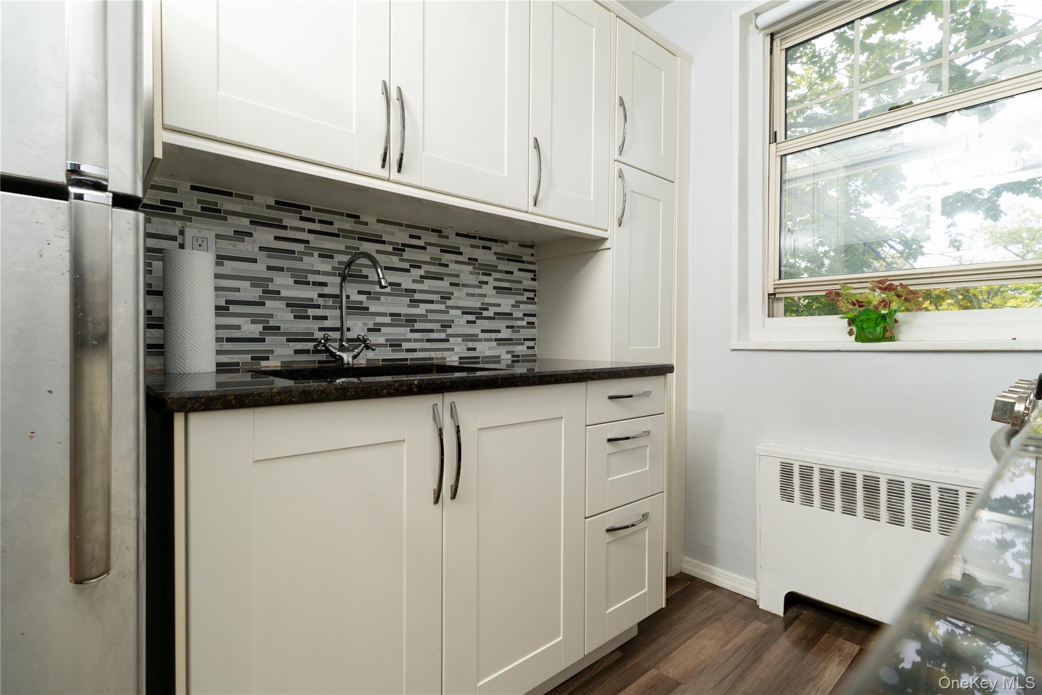 61-15 251st Street, Unit 1100 Queens, NY 11362 - Photo 3 of 17 Kitchen featuring freestanding refrigerator, radiator, tasteful backsplash, and wood finished floors