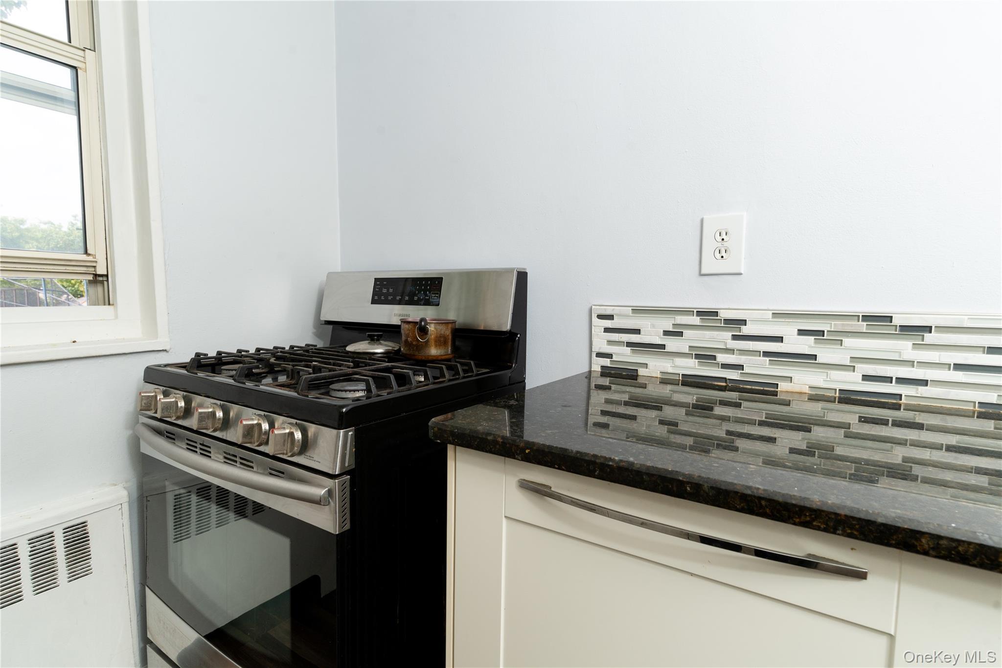 61-15 251st Street, Unit 1100 Queens, NY 11362 - Photo 6 of 17 Kitchen featuring white cabinetry, gas stove, and dark stone countertops