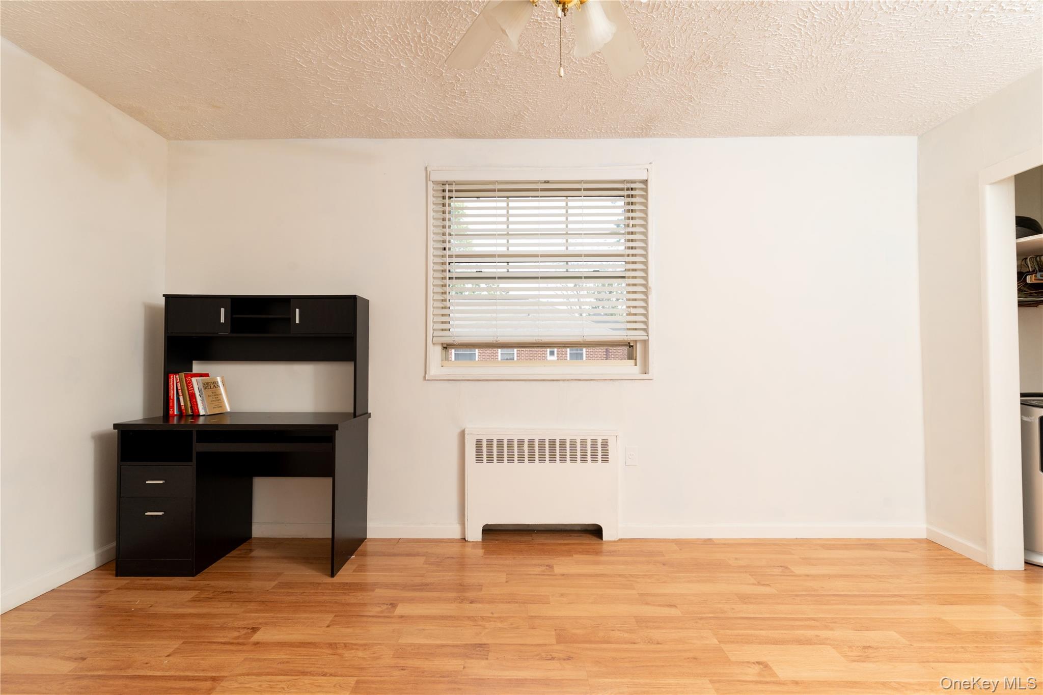 61-15 251st Street, Unit 1100 Queens, NY 11362 - Photo 10 of 17 Bedroom with radiator heating unit, a textured ceiling, light wood-style flooring, and a ceiling fan