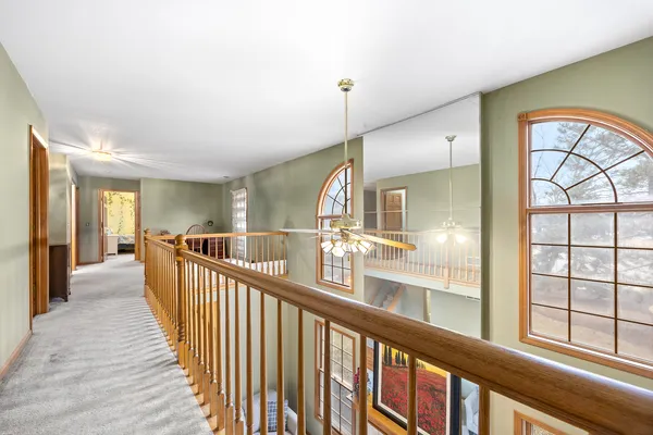 a view of a hallway with wooden floor and windows