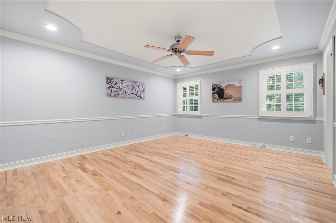 3871 Greentree Road Stow, OH 44224 - Photo 19 of 50 Spacious primary bedroom featuring light wood-finish flooring, two windows with white plantation shutters, and a ceiling fan