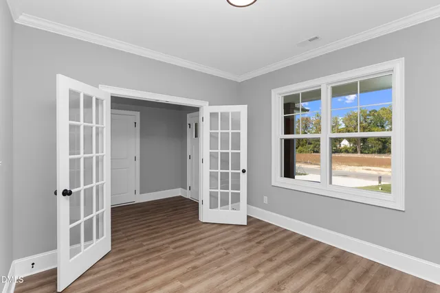 a view of an empty room with wooden floor and a window