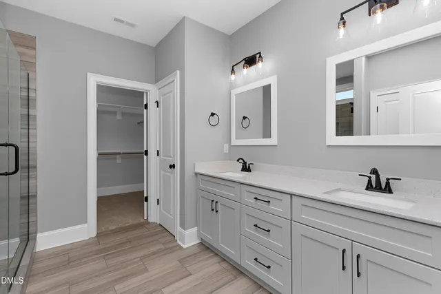 a spacious bathroom with a double vanity sink a mirror and a bathtub