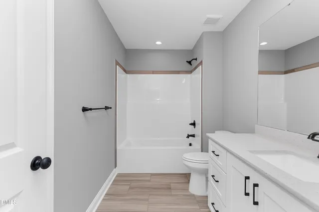 a bathroom with a granite countertop sink a toilet and shower