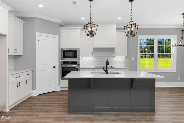 a kitchen with a sink stainless steel appliances and chandelier