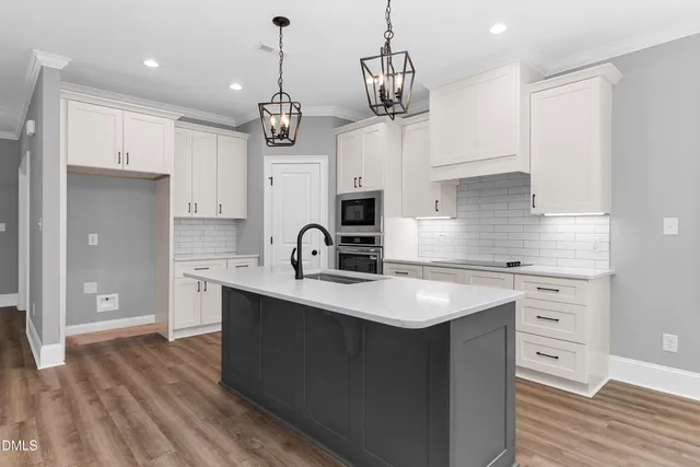 a kitchen with kitchen island granite countertop a sink a counter space appliances and cabinets